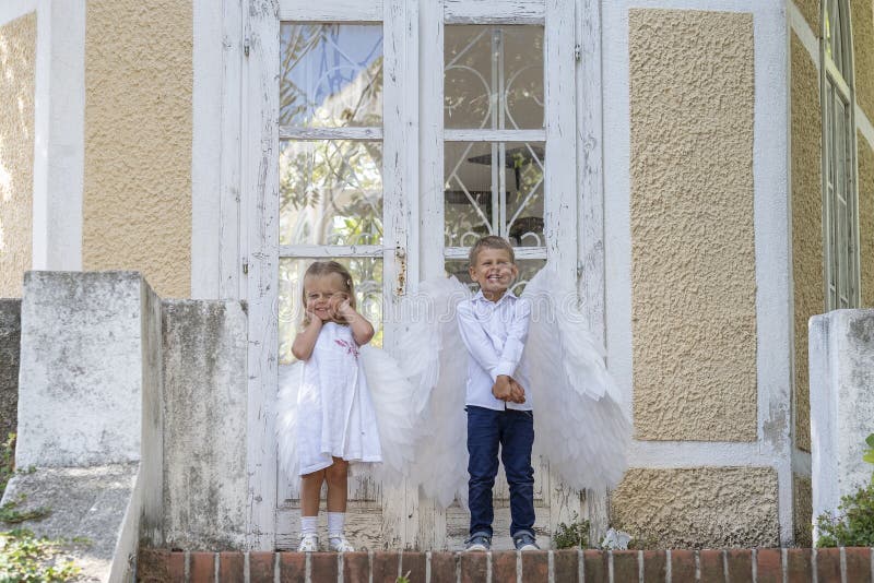? niños vestidos como ángeles parados frente a una puerta cerrada imagen de archivo