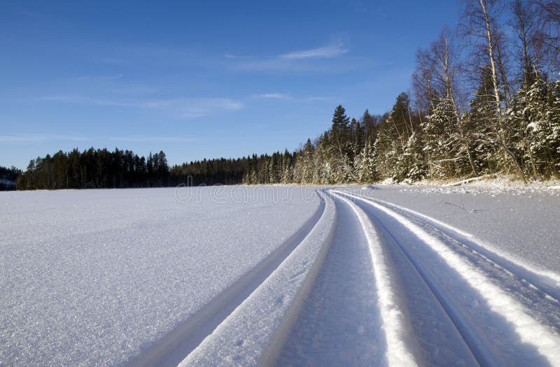 Snowmobile trail on a lake with a blue sky in background, picture from the North of Sweden. Snowmobile trail on a lake with a blue sky in background, picture from the North of Sweden.