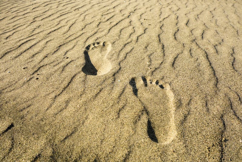 Two footprints (left and right) on a secluded beach of golden sand. Two footprints (left and right) on a secluded beach of golden sand