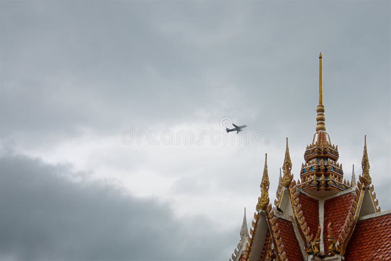 Самолет в облаках шторма над крышей красочного старого тайского виска стоковое изображение Самолет в облаках шторма над крышей красочного старого тайского виска стоковое изображение