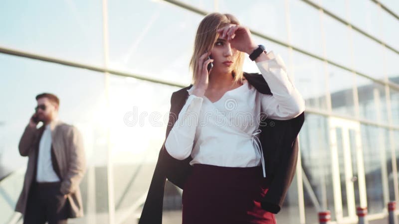 Самоуверенная горячая молодая белокурая девушка готовит крупный аэропорт, говорит на ее телефоне, проверяет время, касается ей