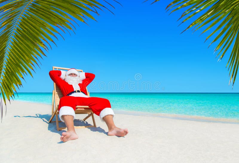 Санта Клаус ослабляет в sunlounger на песочном тропическом Palm Beach стоковые изображения
