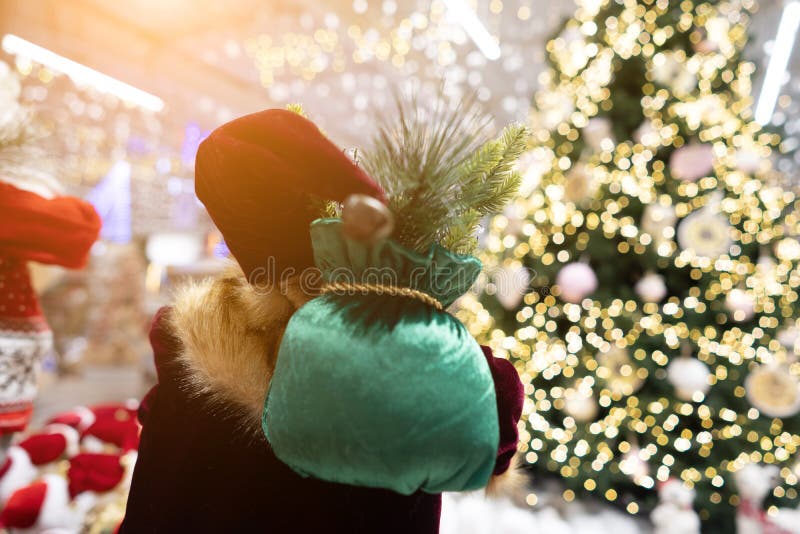 Санта от заднего с сумкой подарка на предпосылке рождественской елки bokeh стоковые изображения