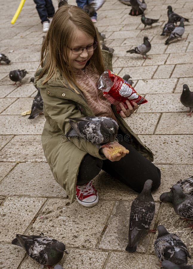 Sarajevo, Bosnia - May 2, 2022 - Young girl feeds the pigeons in a park. Sarajevo, Bosnia - May 2, 2022 - Young girl feeds the pigeons in a park.