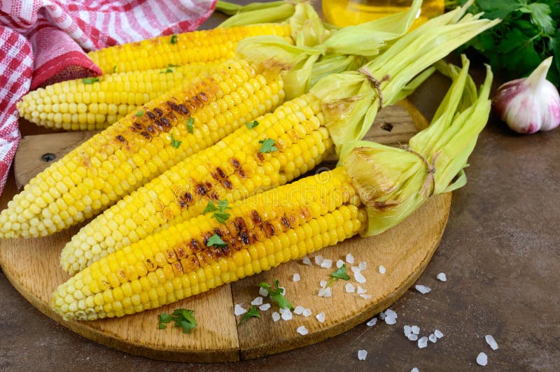 Свежая вкусная зажаренная сладостная мозоль с маслом, солью моря и cilantro на деревянном столе стоковые изображения Свежая вкусная зажаренная сладостная мозоль с маслом, солью моря и cilantro на деревянном столе стоковые изображения