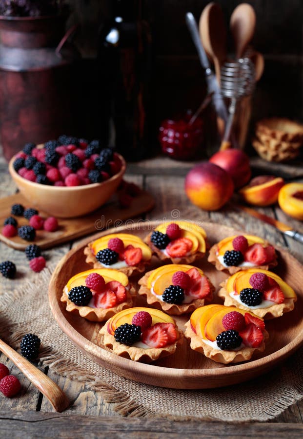 Свежие tartlet или торт ягоды с ванильным заварным кремом, поленикой, персиком и ежевикой Деревенский тип конец вверх стоковое фото