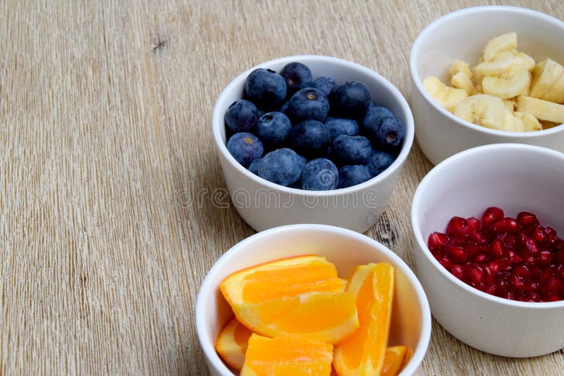 Свежие голубики, банан, pomegrate и оранжевые куски в шарах стоковые изображения Свежие голубики, банан, pomegrate и оранжевые куски в шарах стоковые изображения