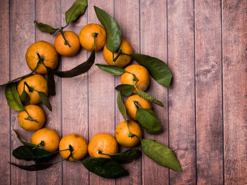 Свежие мандарин или tangerine с стержнями и листьями в форме круга на коричневом деревянном космосе экземпляра предпосылки стоковая фотография Свежие мандарин или tangerine с стержнями и листьями в форме круга на коричневом деревянном космосе экземпляра предпосылки стоковая фотография