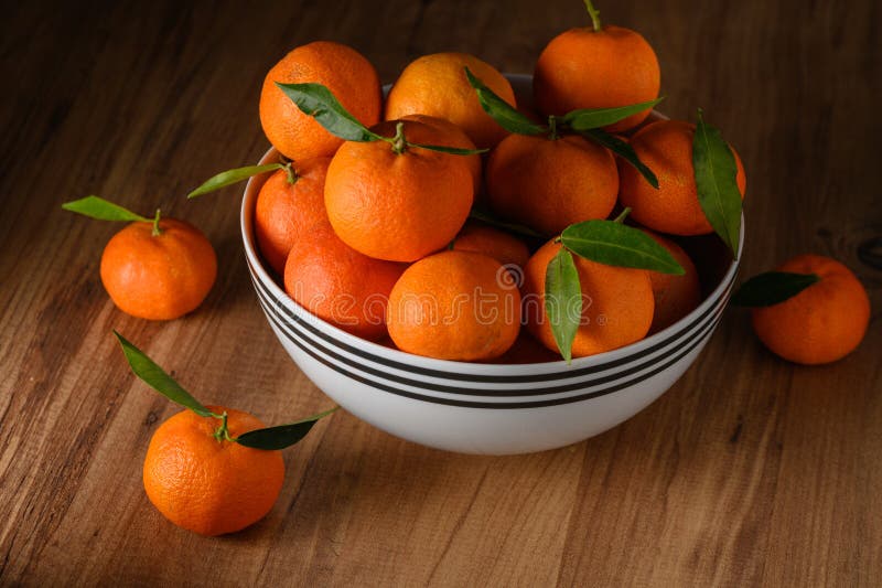 fresh juicy tangerines in a white bowl on a wooden table 2. fresh juicy tangerines in a white bowl on a wooden table 2
