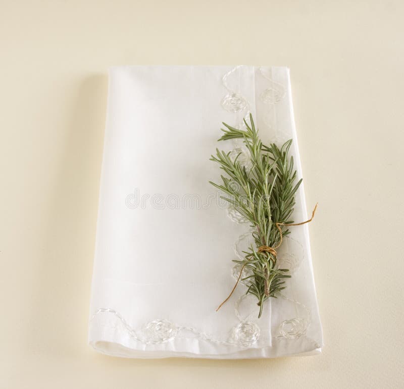 Sprig of fresh rosemary laying on top of a white napkin. Sprig of fresh rosemary laying on top of a white napkin.