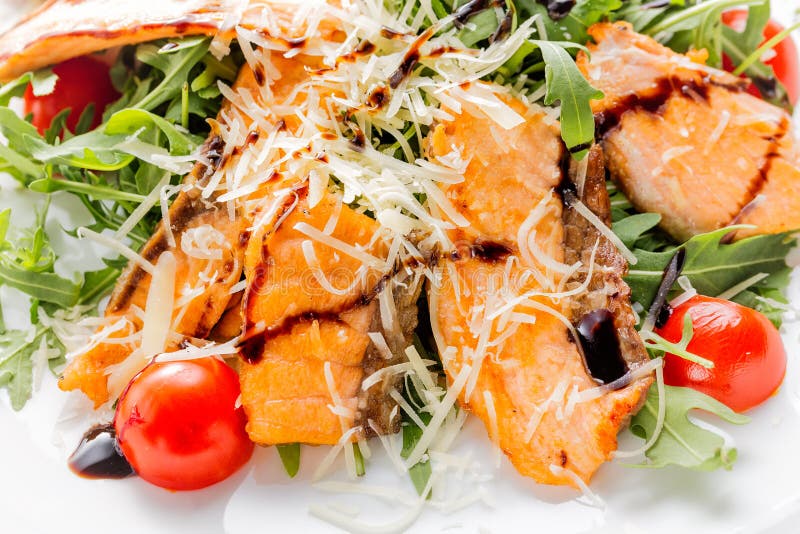 Свежий салат salmon частей, томатов вишни, салата, сыра и соуса на белом конце плиты вверх стоковые изображения Свежий салат salmon частей, томатов вишни, салата, сыра и соуса на белом конце плиты вверх стоковые изображения
