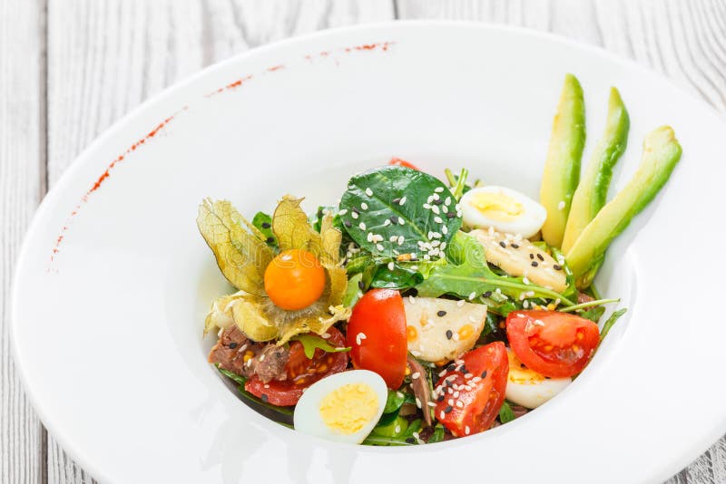 Свежий салат с тунцом, шпинатом, arugula, треской, артишоками, яичками триперсток, авокадоом, томатами вишни, физалисом на деревя стоковое фото Свежий салат с тунцом, шпинатом, arugula, треской, артишоками, яичками триперсток, авокадоом, томатами вишни, физалисом на деревя стоковое фото