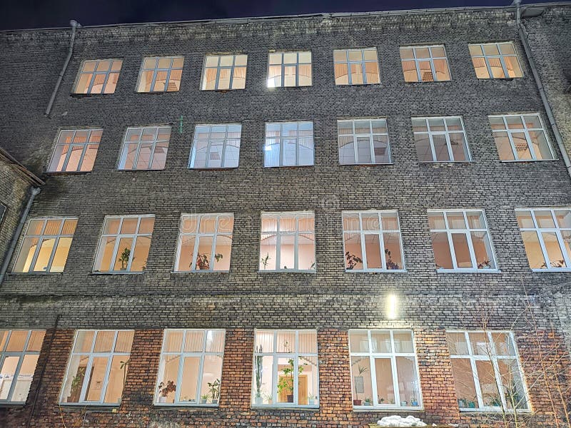 светлые окна кирпичного офисного здания после наступления темноты. офисное здание с подсветкой в ночное время стоковая фотография