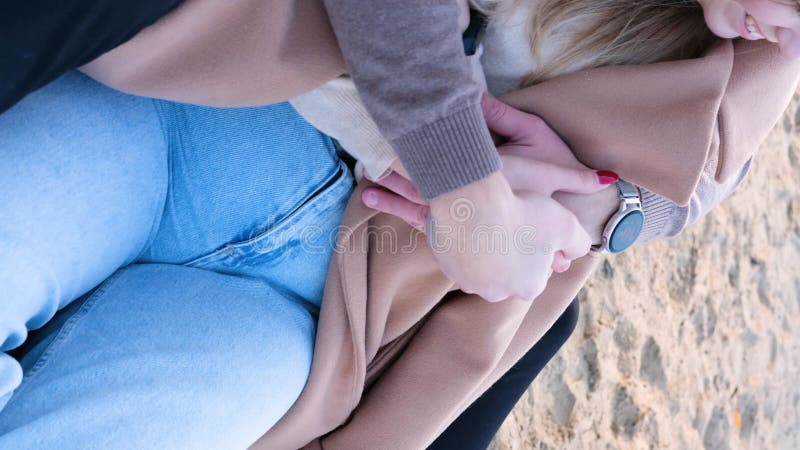 свидание на пляже. молодая пара в свитерах сидит на одеяле, а парень обнимает плечи девочек. закрытие