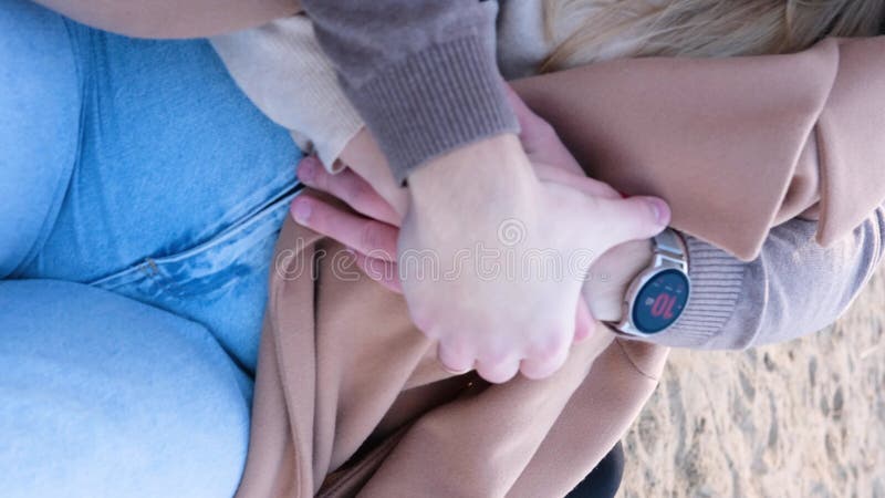 свидание на пляже. молодая пара в свитерах сидит на одеяле, а парень обнимает плечи девочек. закрытие