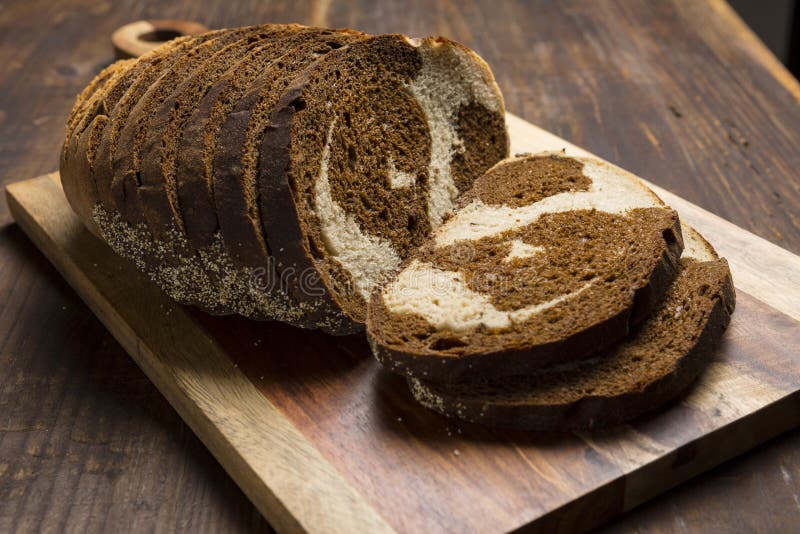 Свирль Pumpernickel и рож обваливает куски в сухарях на разделочной доске стоковые изображения Свирль Pumpernickel и рож обваливает куски в сухарях на разделочной доске стоковые изображения