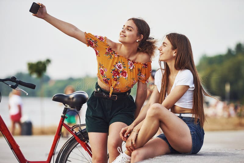 Сделать selfie. 2 Молодой женщины с велосипедом хорошо проводите время в парке стоковые фотографии rf