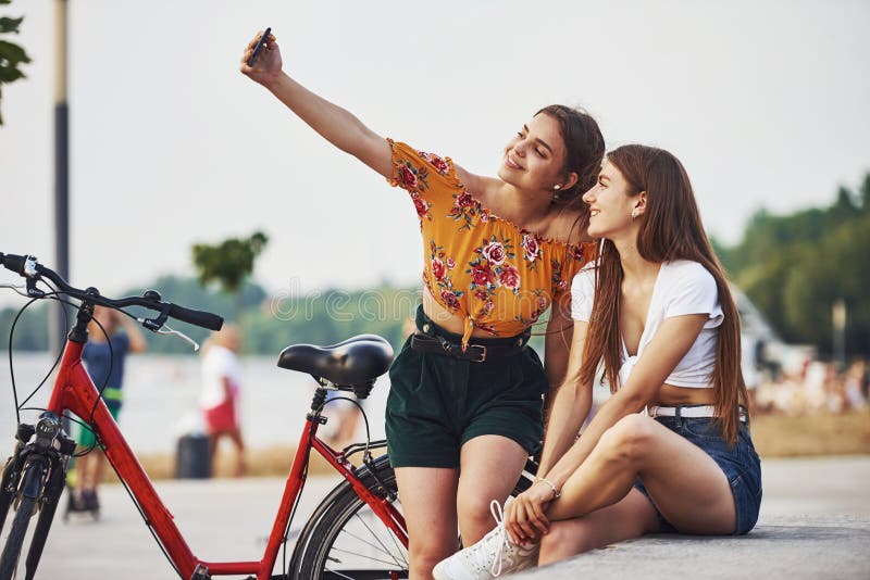 Сделать selfie. 2 Молодой женщины с велосипедом хорошо проводите время в парке стоковые изображения