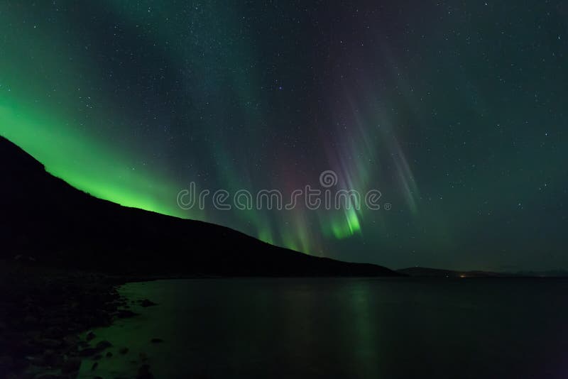 Aurora Borealis in Northern Norway, green light lights up the scenery and makes the mountaines pop out in silouette. Aurora Borealis in Northern Norway, green light lights up the scenery and makes the mountaines pop out in silouette