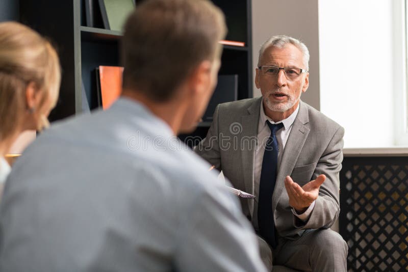 Седой уверенный профессиональный симпатичный psychotherapist советуя с женатыми парами стоковое фото
