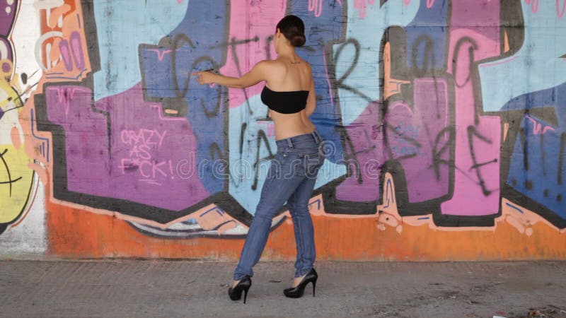 Сексуальные танцы женщины перед стеной граффити