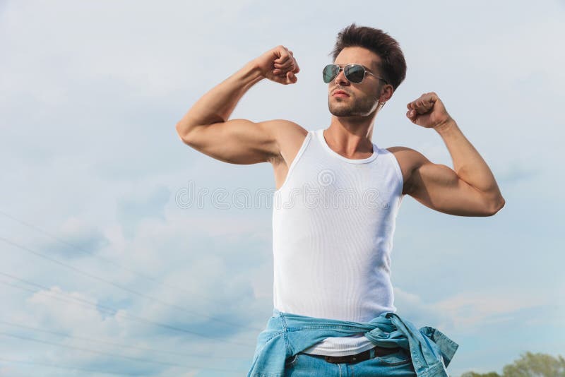 Сексуальный человек в undershirt изгибая его бицепс снаружи стоковые фотографии rf