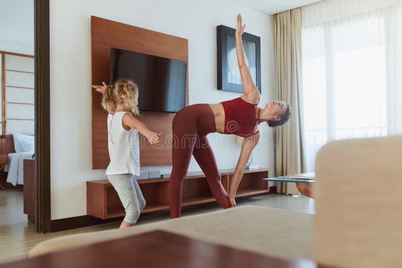 Family. Mother And Child Exercising At Home. Little Girl And Young Woman Practicing Together In Living Room. Workout Routine For Active Lifestyle. Family. Mother And Child Exercising At Home. Little Girl And Young Woman Practicing Together In Living Room. Workout Routine For Active Lifestyle