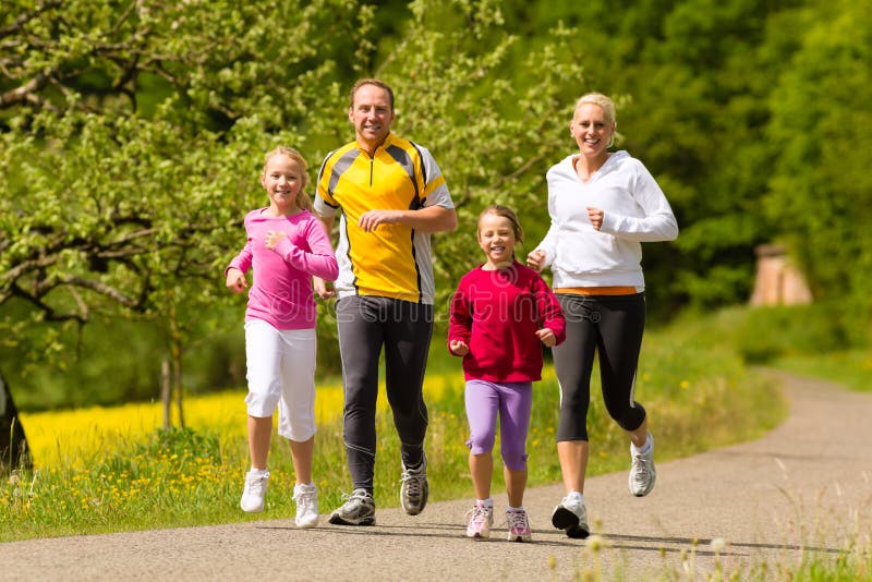 Happy Family with two girls running or jogging for sport and better fitness in a meadow in summer. Happy Family with two girls running or jogging for sport and better fitness in a meadow in summer