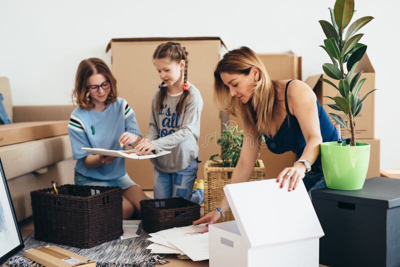 Семья с картонными коробками в новом доме на moving дне стоковые изображения Семья с картонными коробками в новом доме на moving дне стоковые изображения