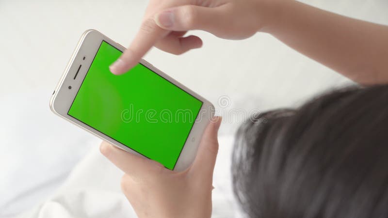 Сенсорный смартфон молодой женщины, лежащего и зеленого экрана для наблюдения за видео девочки, используя телефон,- испуганно соци сток-видео