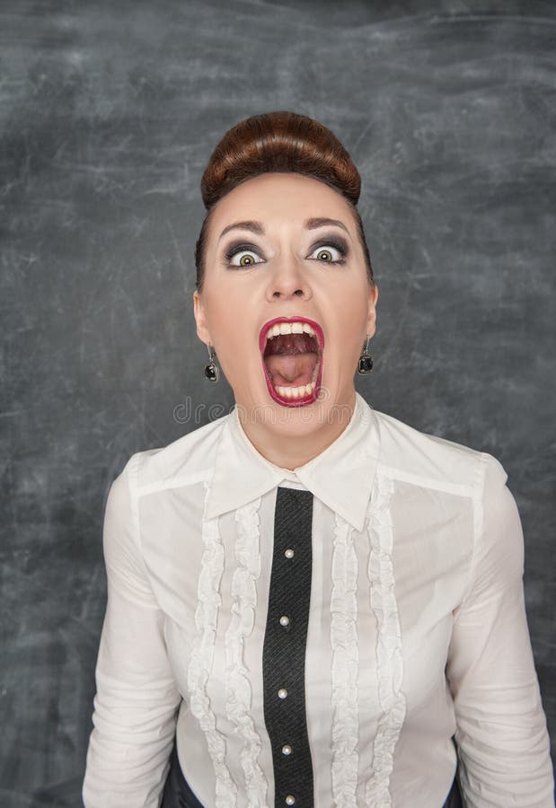 Angry screaming woman on the blackboard background. Angry screaming woman on the blackboard background