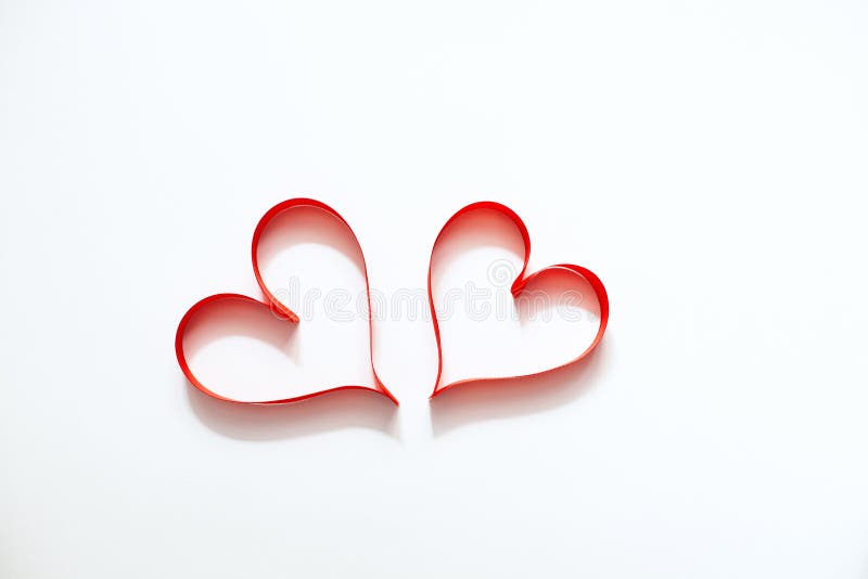 Two hearts from a red satin ribbon in the form of a heart on a white background, the concept of Valentine`s Day, a gift, a declaration of love. Two hearts from a red satin ribbon in the form of a heart on a white background, the concept of Valentine`s Day, a gift, a declaration of love