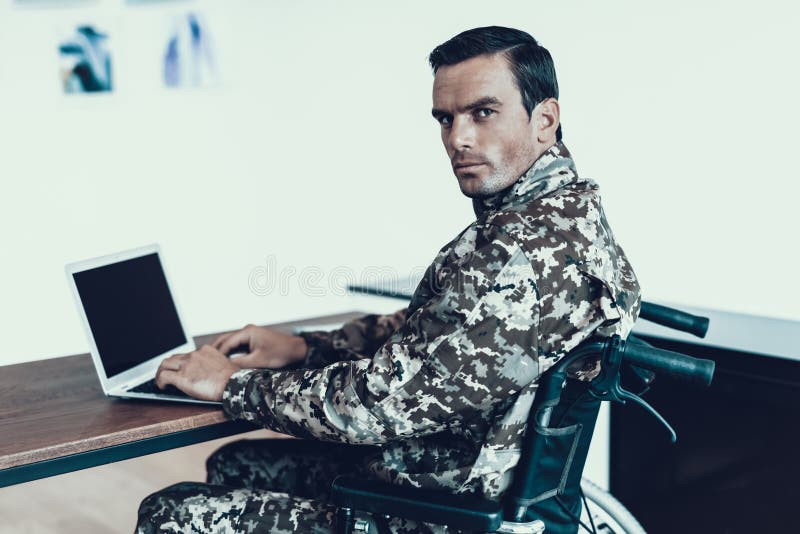 Серьезный военный в работе кресло-коляскы на компьтер-книжке стоковое изображение rf Серьезный военный в работе кресло-коляскы на компьтер-книжке стоковое изображение rf