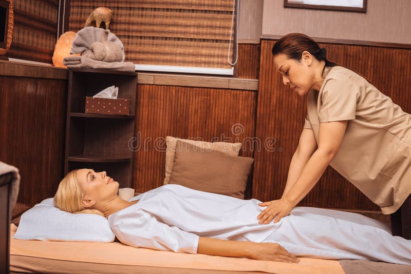 Серьезный умелый азиатский masseuse выполняя массаж стоковые изображения Серьезный умелый азиатский masseuse выполняя массаж стоковые изображения