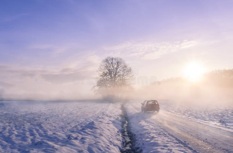 Winter image with the silhouette of a car driving on a snowy country road, through mist and the sunrise light. Winter image with the silhouette of a car driving on a snowy country road, through mist and the sunrise light.