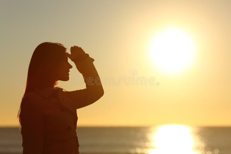 Силуэт женщины смотря вперед на заходе солнца