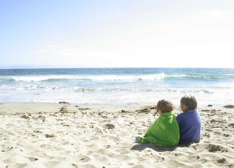 2 girls sitting on the beach wrapped in towels after swimming. 2 girls sitting on the beach wrapped in towels after swimming.