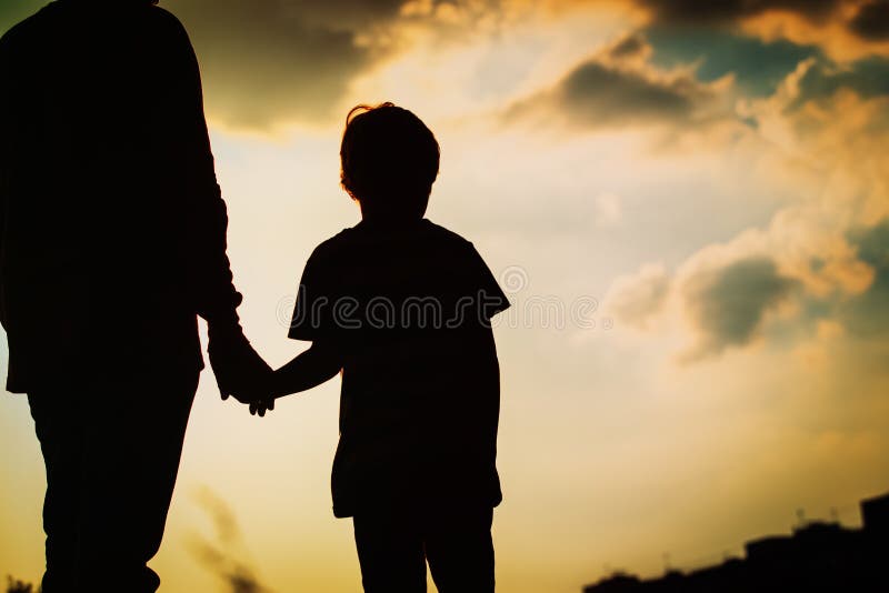 Silhouette of father and son holding hands at sunset sky. Silhouette of father and son holding hands at sunset sky