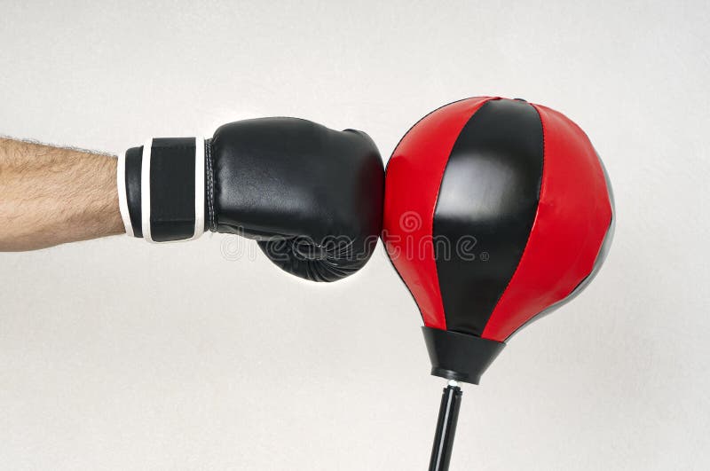 A strong man`s hand in a boxing glove hits the floor punching bag. Closeup view. A strong man`s hand in a boxing glove hits the floor punching bag. Closeup view