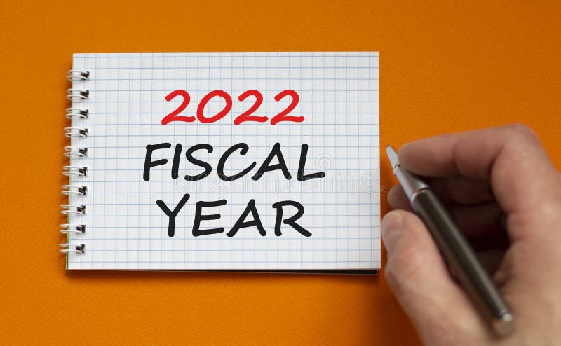 символ нового финансового года 2022. бизнесмен пишет слова 2022 финансовый  год на белой ноте. красивый оранжевый фон. бизнес Стоковое Фото -  изображение насчитывающей дело, счастливо: 227681198
