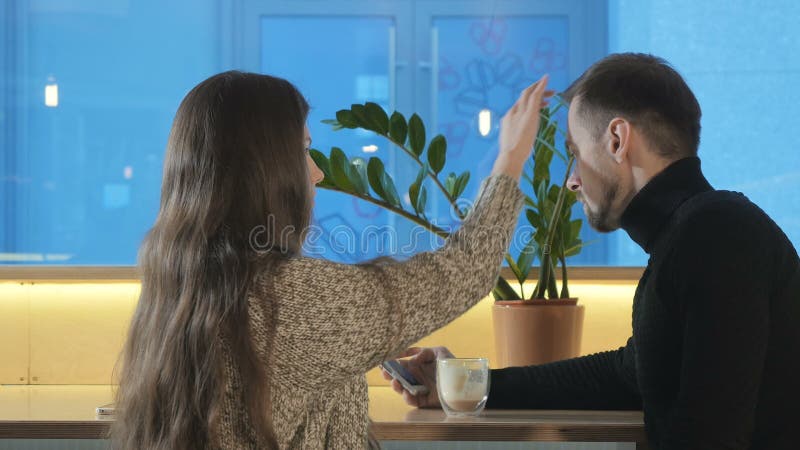Симпатичное касание девушки волосы ` s парня в кафе акции видеоматериалы