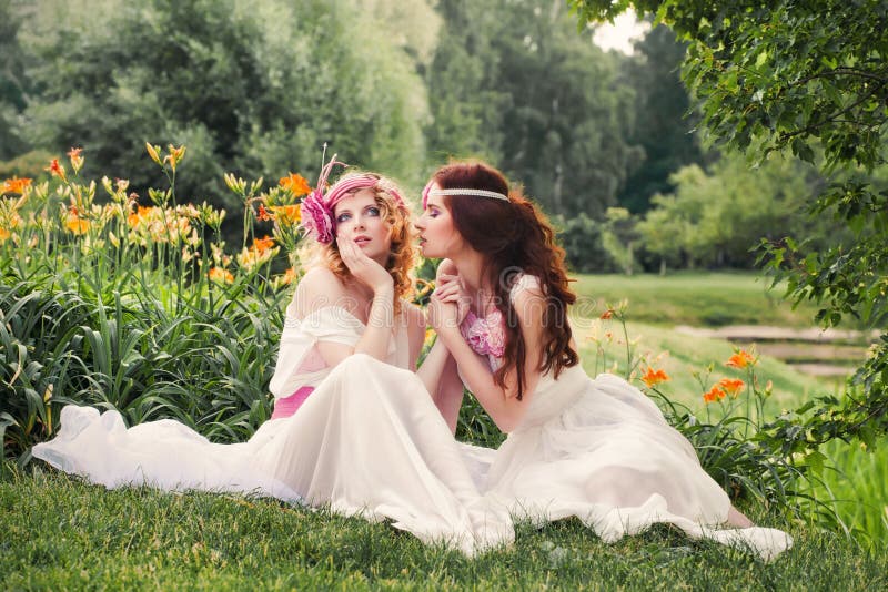 Симпатичные bridesmaids сидя на траве стоковые фото Симпатичные bridesmaids сидя на траве стоковые фото