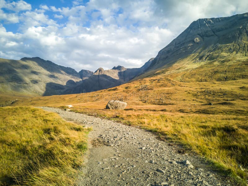Сиротливый путь к бассейнам феи перед черными горами Cuillin на острове Skye - Шотландии стоковая фотография rf Сиротливый путь к бассейнам феи перед черными горами Cuillin на острове Skye - Шотландии стоковая фотография rf