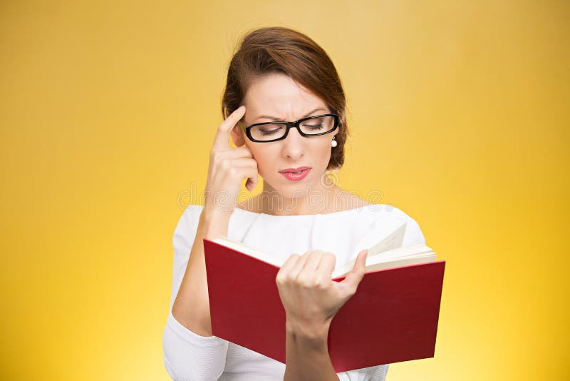 Young elegant woman in eyeglasses having problems with understanding while reading book isolated on yellow background. Young elegant woman in eyeglasses having problems with understanding while reading book isolated on yellow background