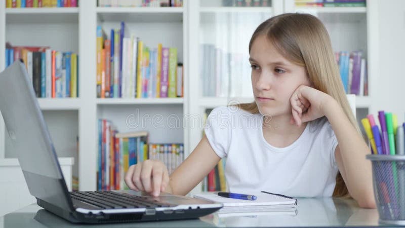 скучающая девочка учится на ноутбуке для школьного грустного ребенка, работающего на Pc в офисе ученика, который пишет домашнее за видеоматериал