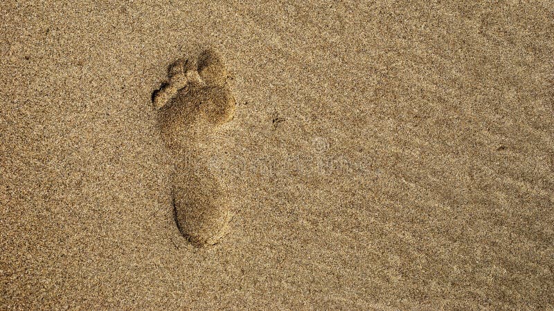 A single footprint in the sand from sraight above. A single footprint in the sand from sraight above