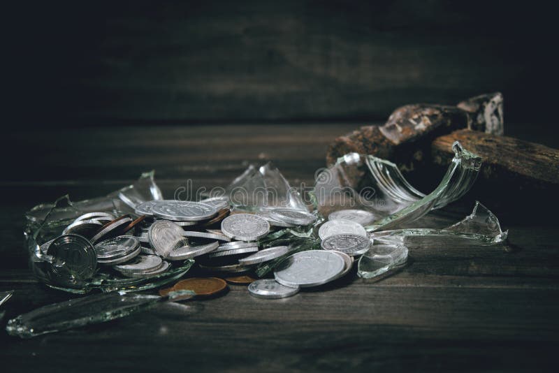 broken savings bank and coins next to a hammer. broken savings bank and coins next to a hammer.