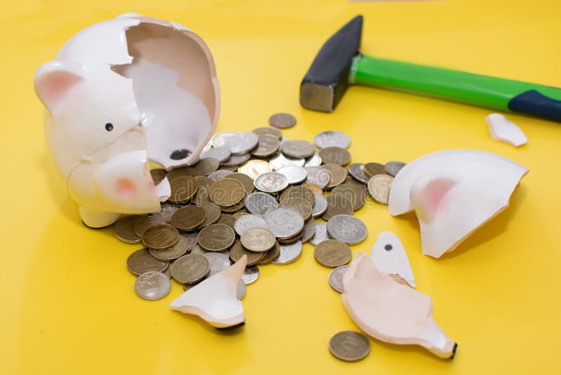 Broken piggy Bank in the form of a pig, with a hammer and coins on a yellow background. Broken piggy Bank in the form of a pig, with a hammer and coins on a yellow background.