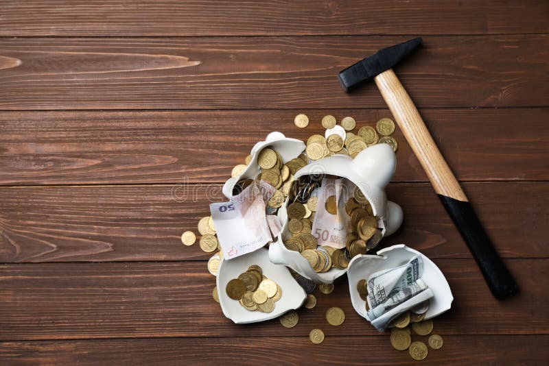 Broken piggy bank with money and hammer on wooden background, top view. Space for text. Broken piggy bank with money and hammer on wooden background, top view. Space for text