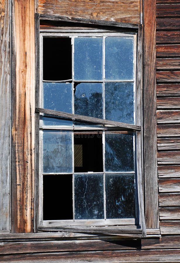 Weathered wood siding and sashes frame a broken and deteriorating 12 pane window. Weathered wood siding and sashes frame a broken and deteriorating 12 pane window.